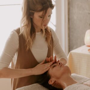 Mujer recibiendo un masaje facial mientras otra mujer aplica técnicas de relajación.